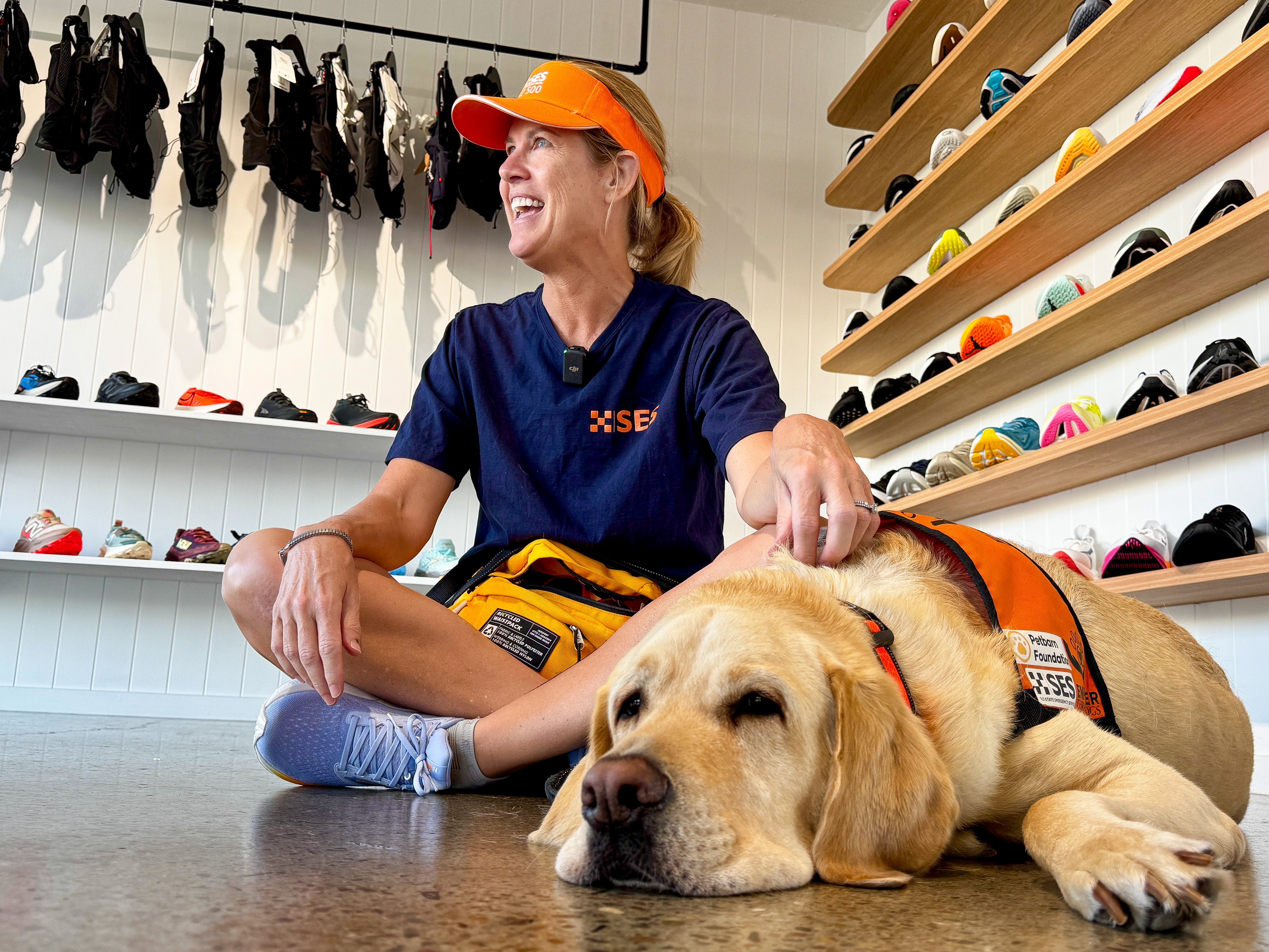 Macca the support dog and his handler sitting on the floor in a shoe store