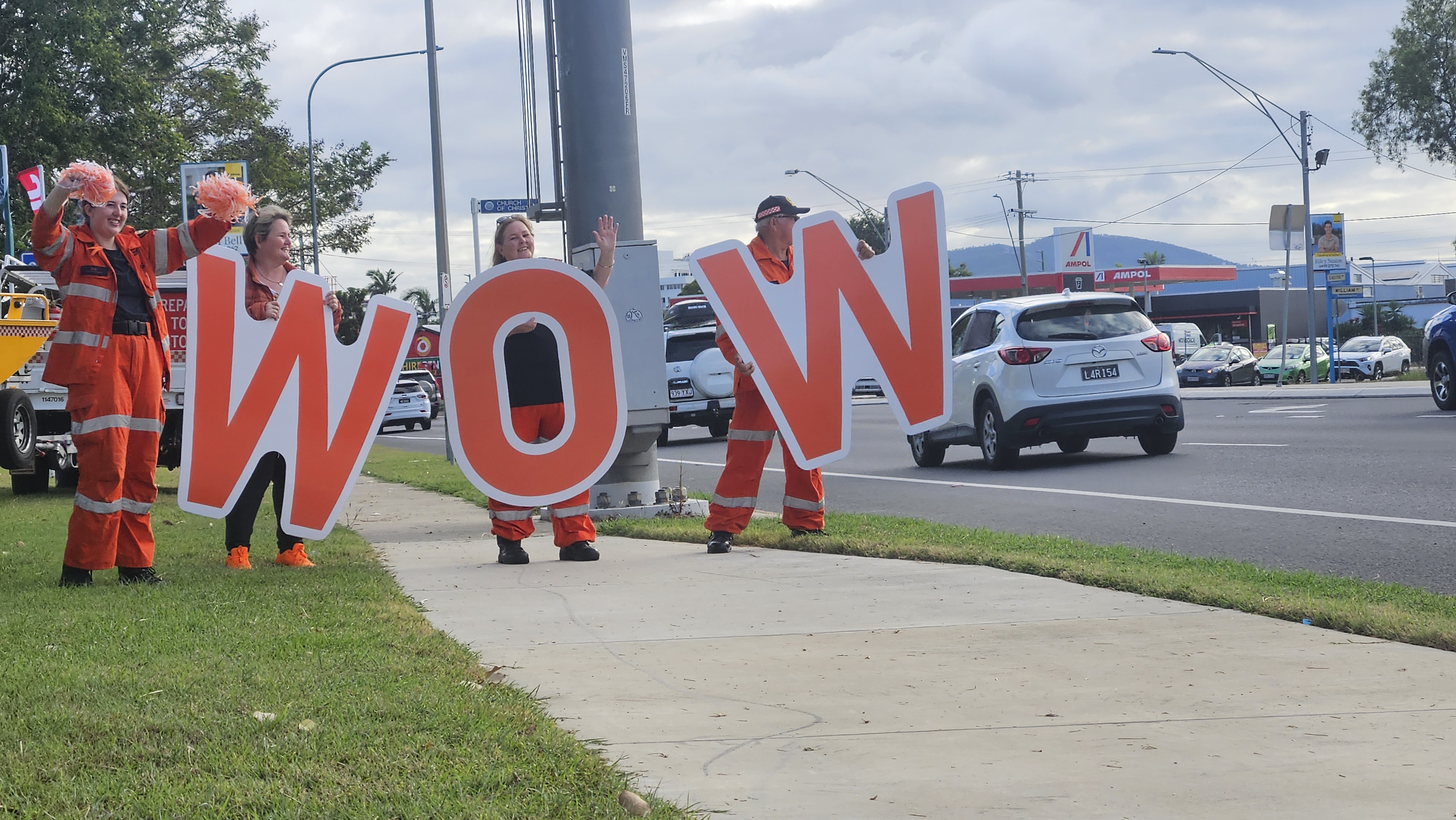 SES volunteers hold WOW letters on the side of the street.