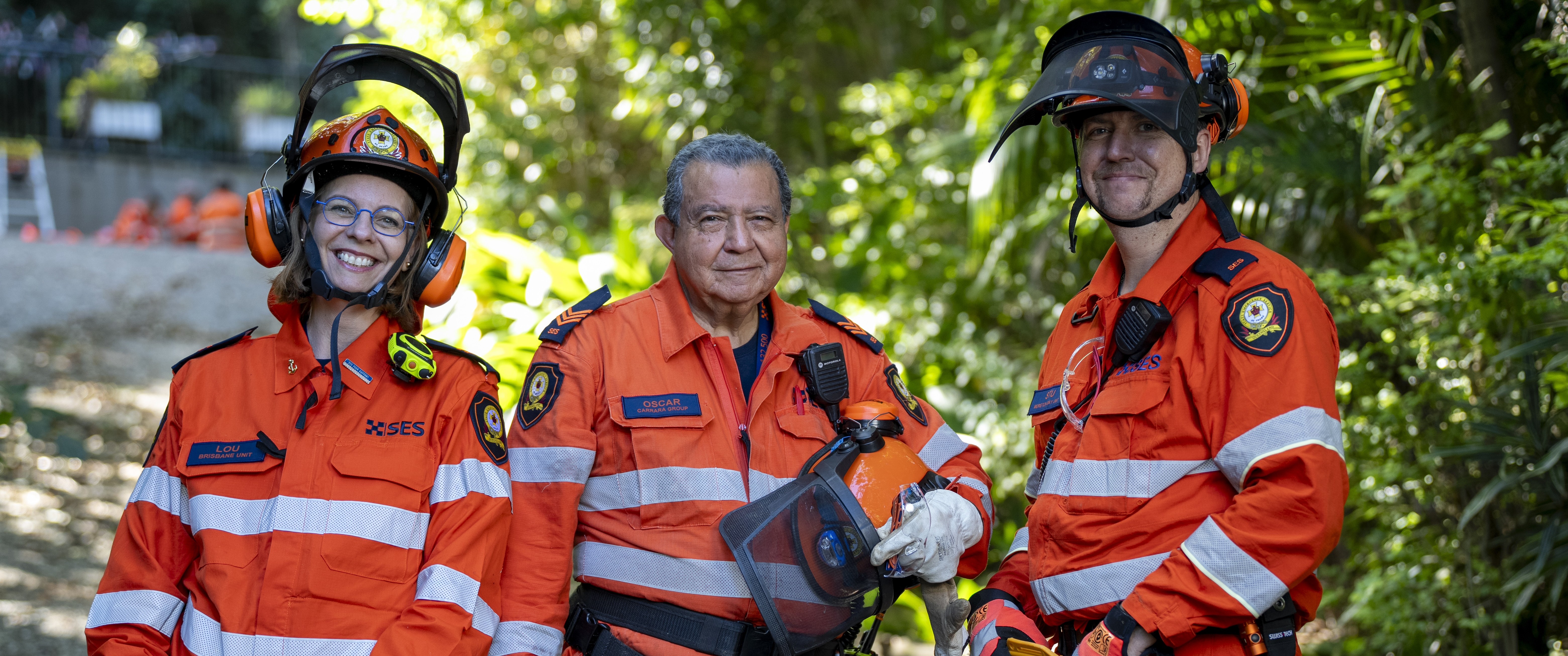 3 SES Volunteers standing outdoors. They are wearing PPE with helmets.