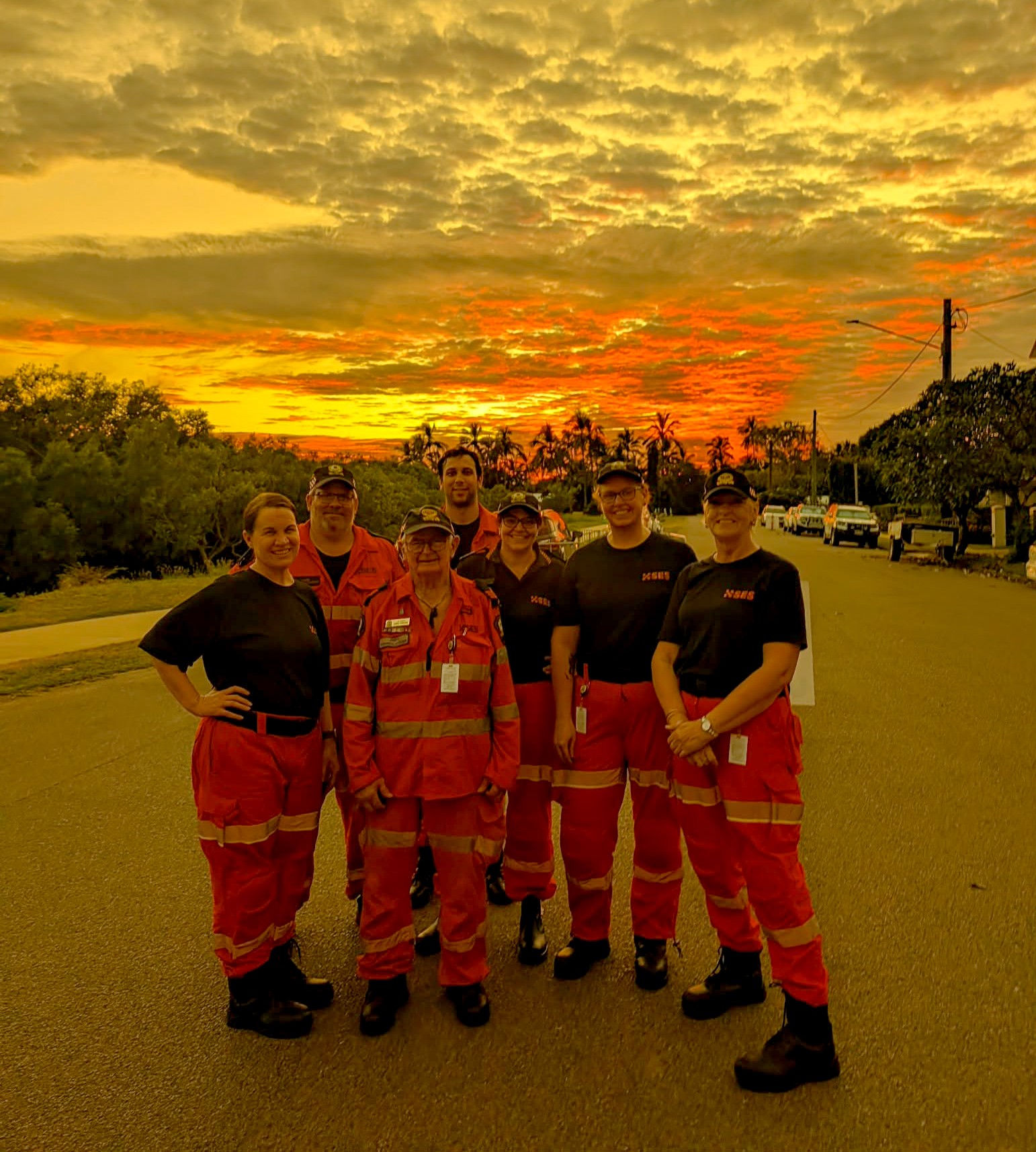 SES members in a group standing in front of a cloudy sunrise.