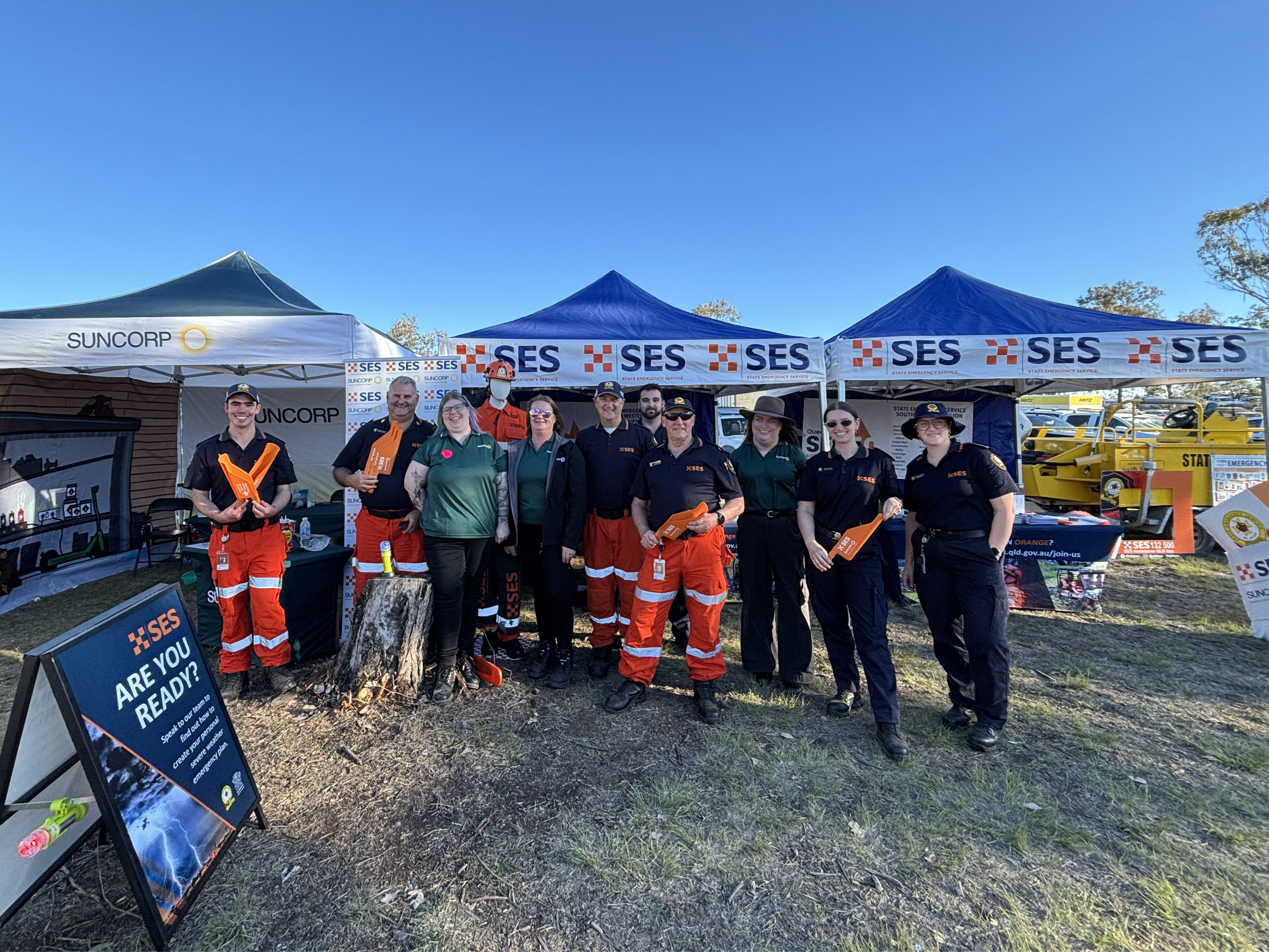 Group of 8 SES volunteers standing in front of stall at Farmfest along with 2 Suncorp representatives.