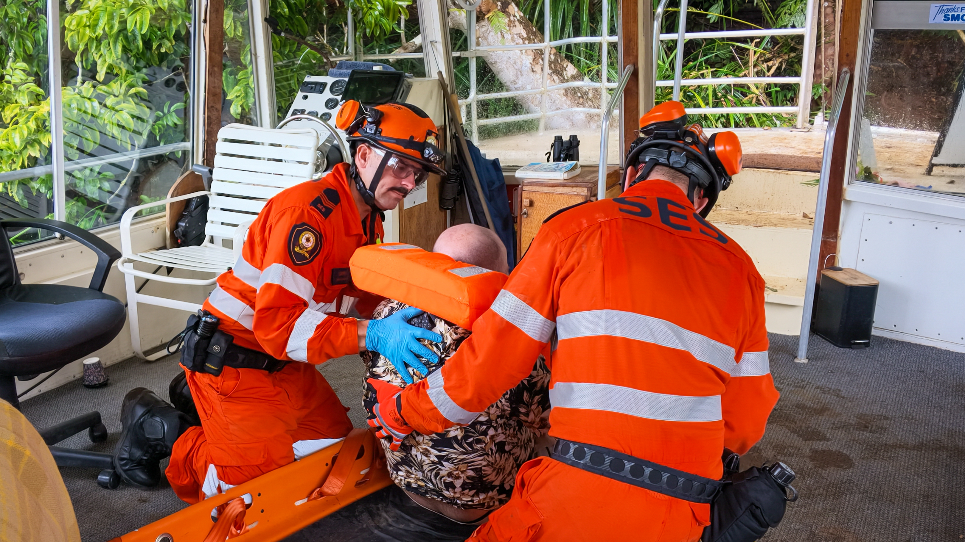Two members of the Queensland SES NDRC team working together to support an actor is a planned scenario on a river boat.