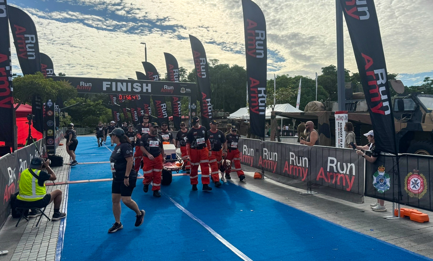 Run Army finish line with banners and flags on each side of a blue track. SES members are walking through the finish line.